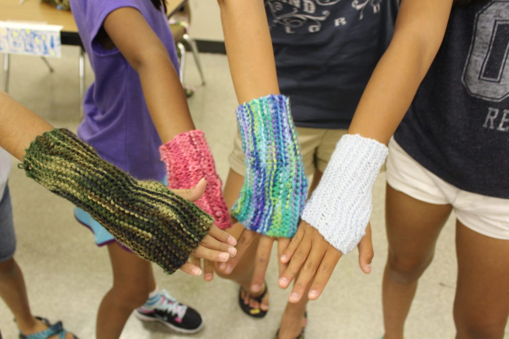 young girls showing off their finished knit mitts