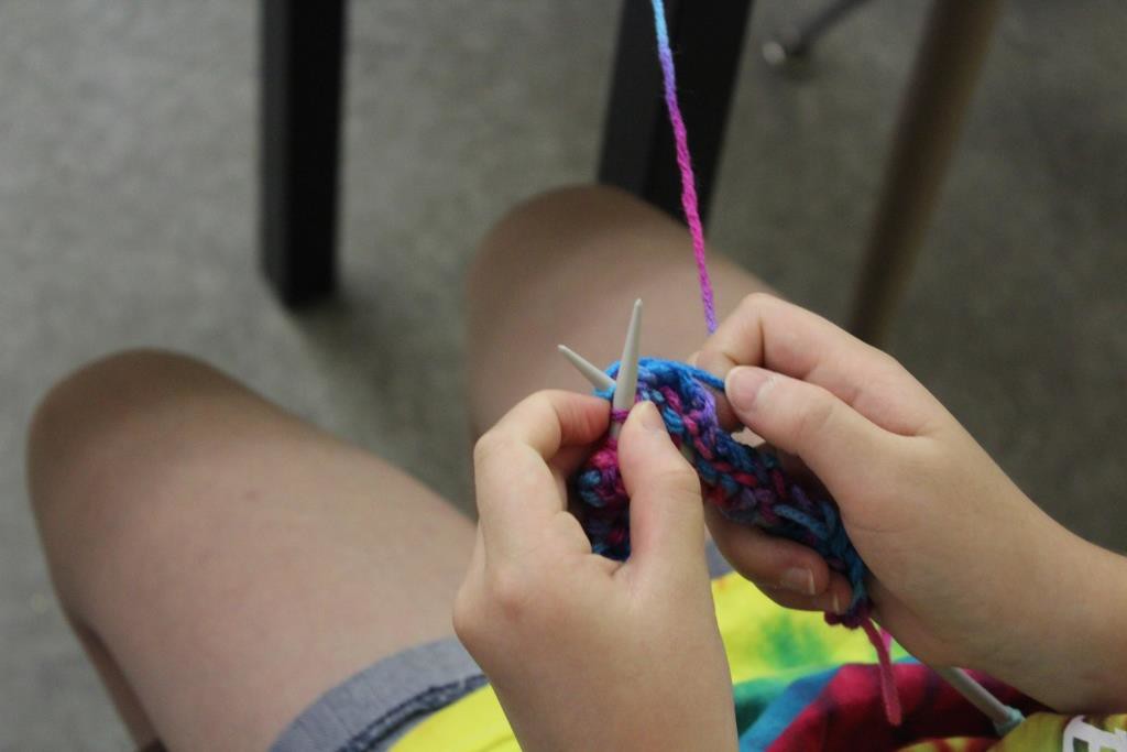 Child learning to knit with multicolored yarn