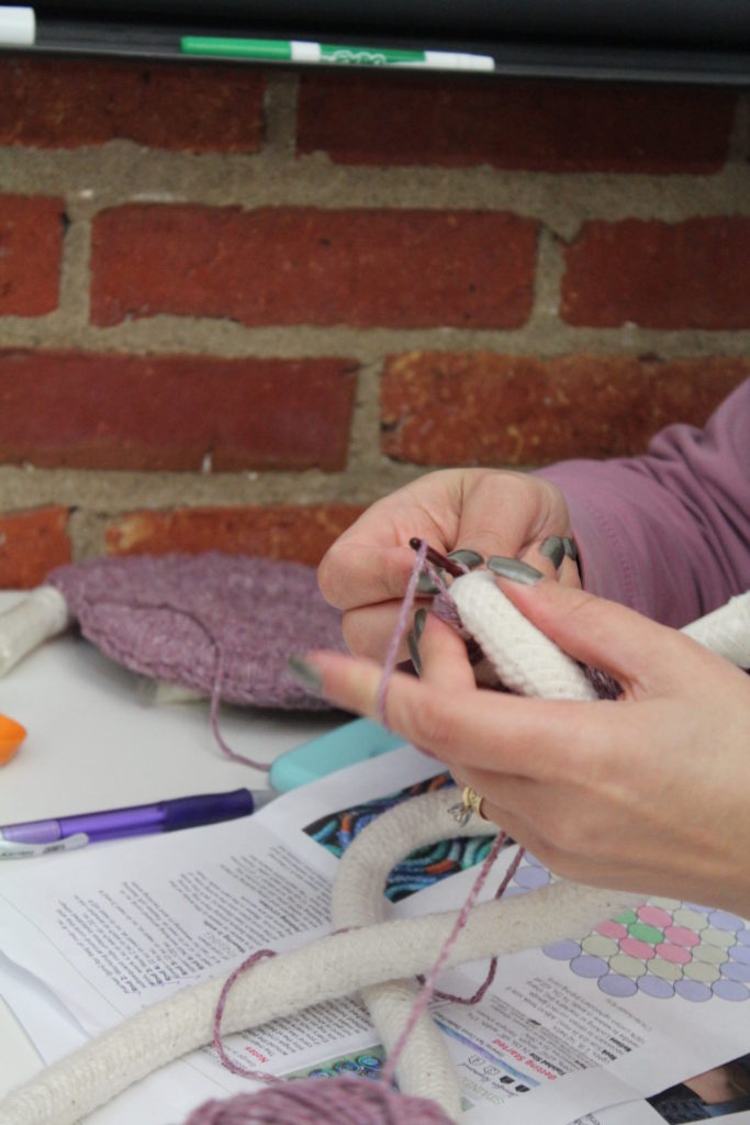 Woman working on padded crochet motif.