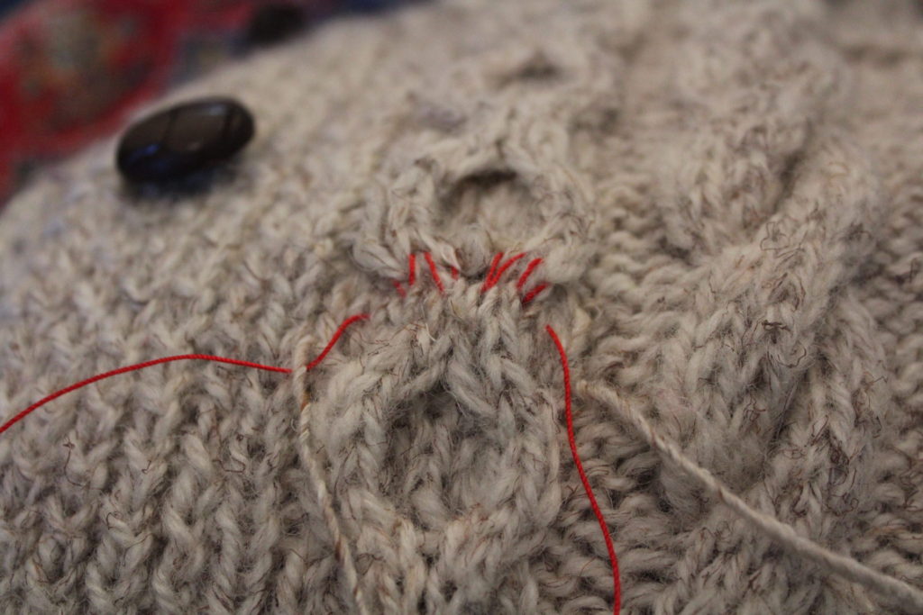 Sweater repair half done, only red guidelines remain.