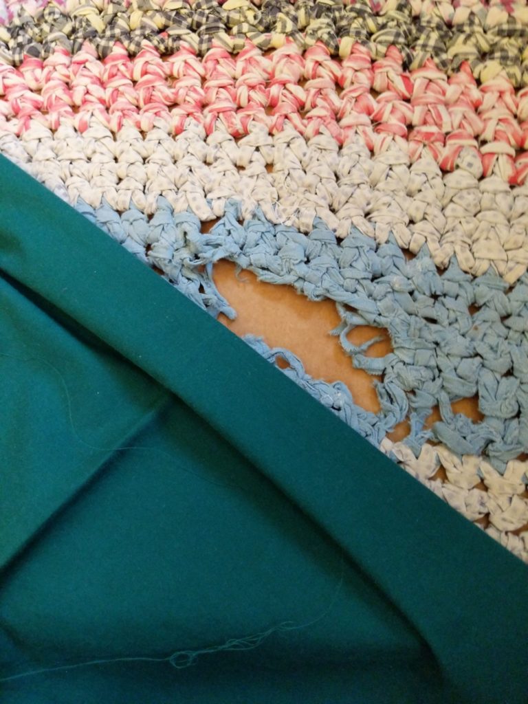 teal sheet fabric against damaged rag rug