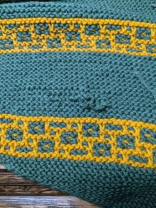 recently rewoven hole in garter stitch shawl in green and gold, threads are still visible